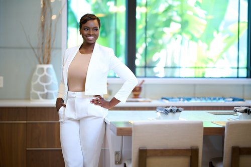 Branding portrait in a white pantsuit beside a dining table