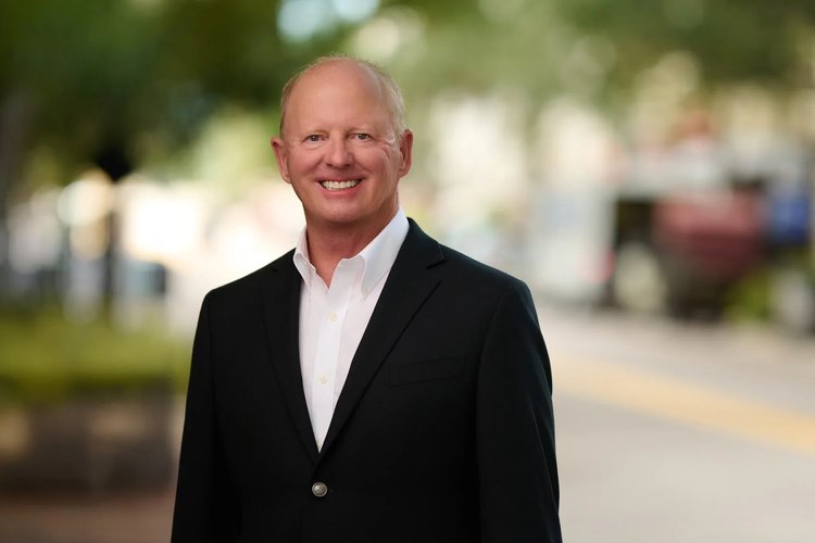 Outdoor headshot of a smiling real estate professional.