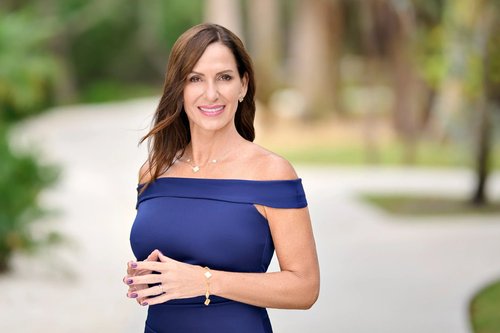 Outdoor portrait in an off-the-shoulder navy dress beside a palm-lined path