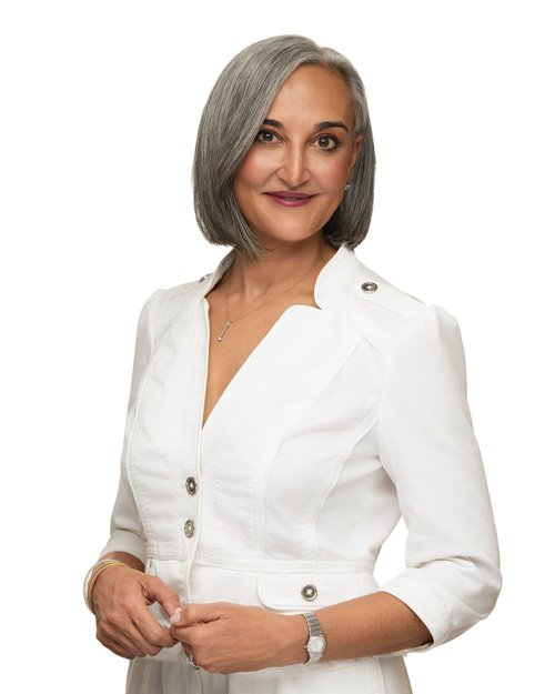 Professional portrait in a white blazer with a gray bob against a white backdrop