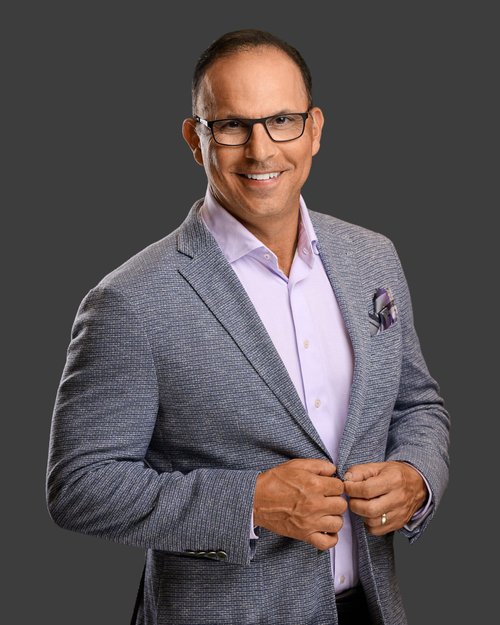 Business portrait in glasses and a gray blazer against a dark gray backdrop