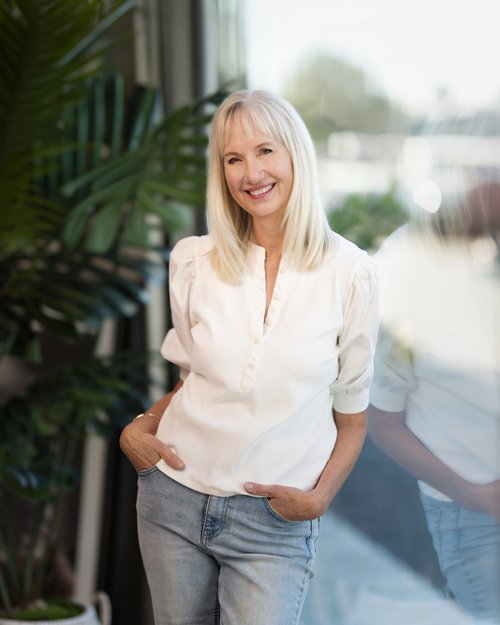 Portrait in a white blouse and jeans beside a window