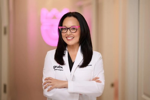 Portrait in a white medical coat and pink glasses inside a clinic