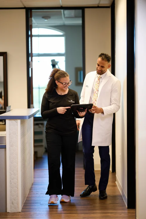 Workplace branding photograph of two people reviewing a tablet in a clinic hallway