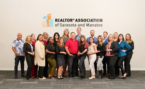 Group portrait beneath the REALTOR Association of Sarasota and Manatee sign