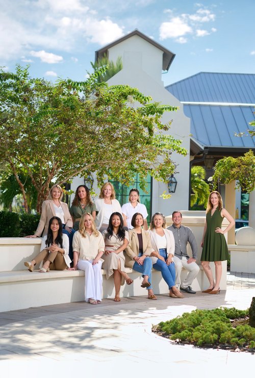 Outdoor team portrait on steps beside a tree and a white building