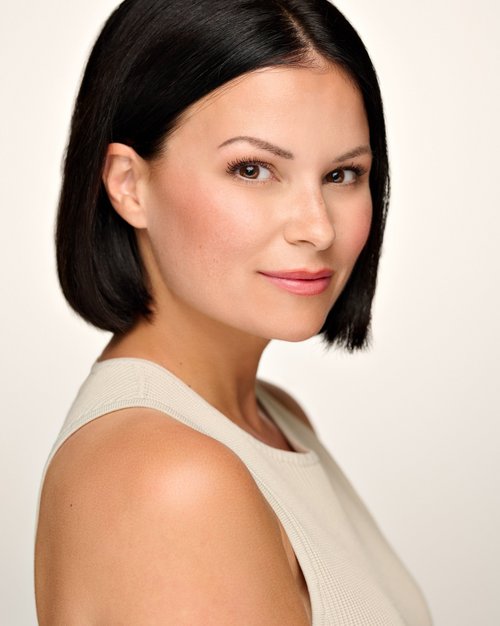 Talent headshot with a dark bob and cream sleeveless top against a light backdrop