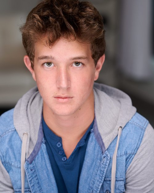 Talent headshot in a denim jacket with a gray hood over a blue shirt