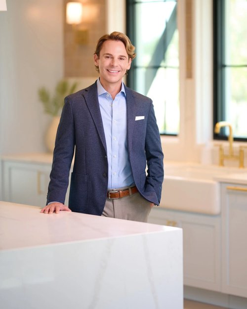 Portrait in a navy blazer and light blue shirt beside a kitchen island