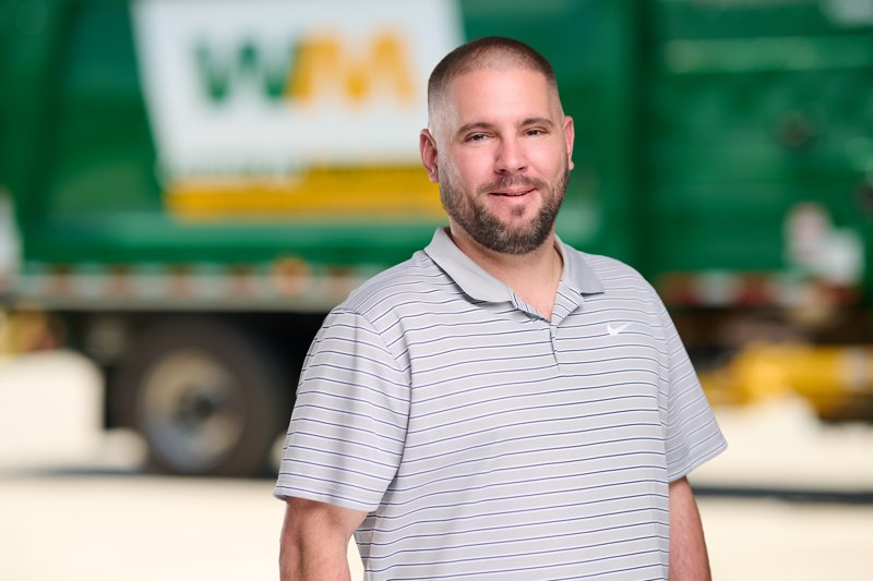 Staff portrait in a striped polo in front of a WM truck