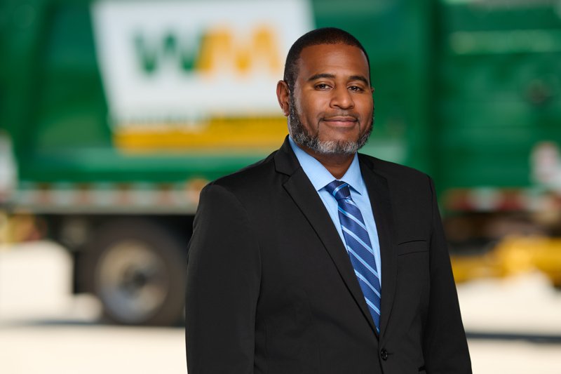 Staff portrait in a black suit and blue tie in front of a WM truck