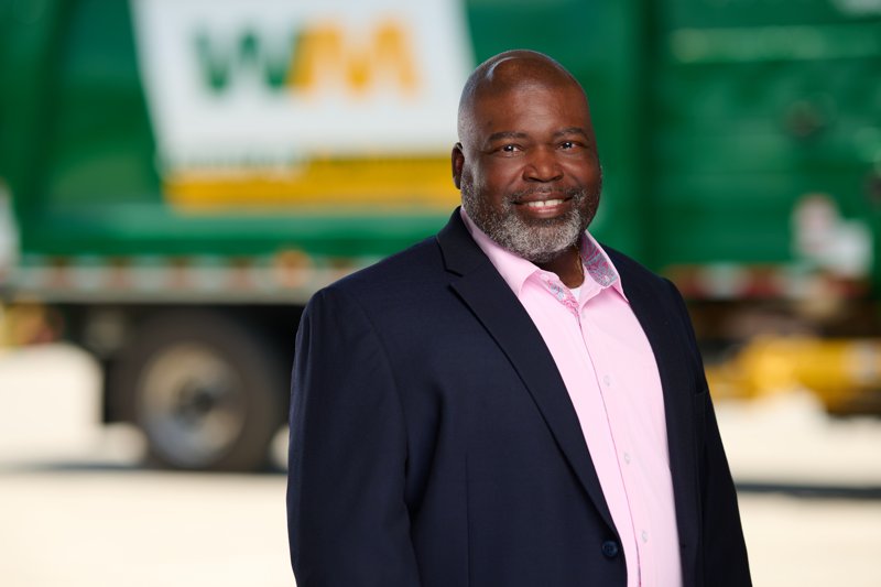 Staff portrait in a navy blazer and pink shirt in front of a WM truck
