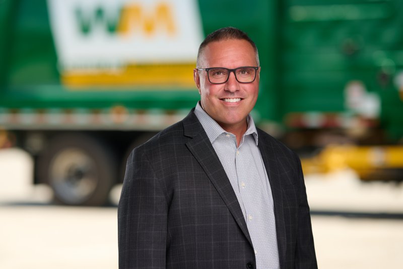 Staff portrait in glasses and a dark blazer in front of a WM truck