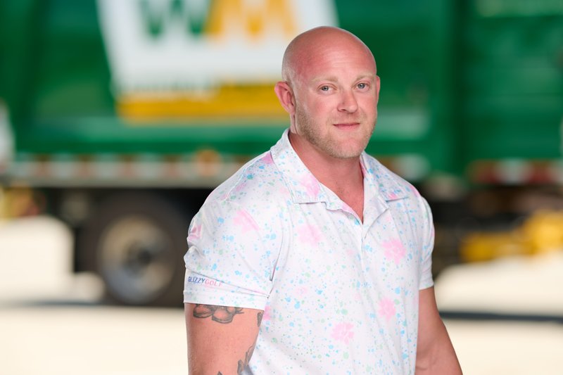 Staff portrait in a patterned polo in front of a WM truck